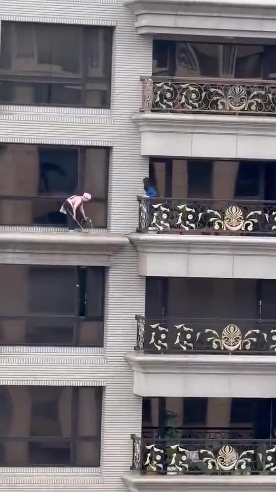 太危险了!一人站在高空楼沿清理卫生!