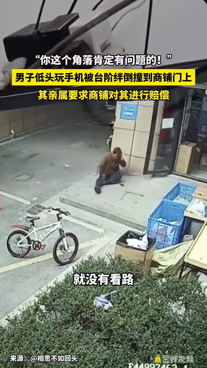 男子低头玩手机被台阶绊倒撞到商铺门上