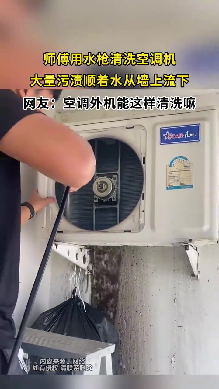 师傅用水枪清洗空调机，大量污渍顺着水从墙上流下！