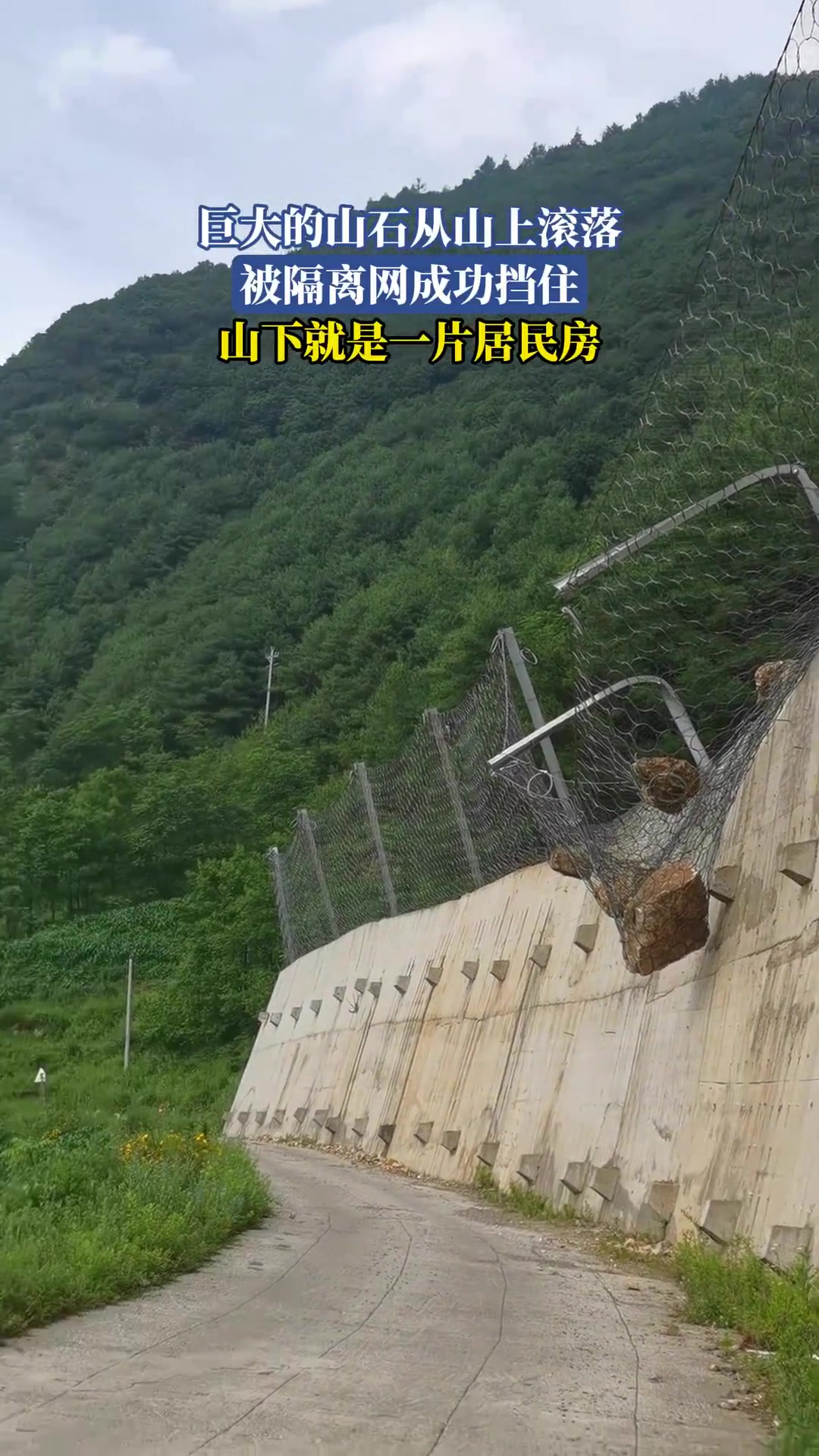 巨大的落石从山上滚下，被隔离网成功挡住，山下就是一片居民房