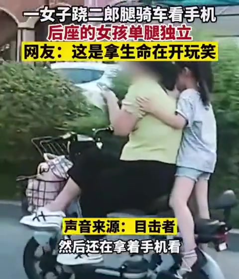一女子单手骑电动车带孩子 边骑车边看手机还跷二郎腿