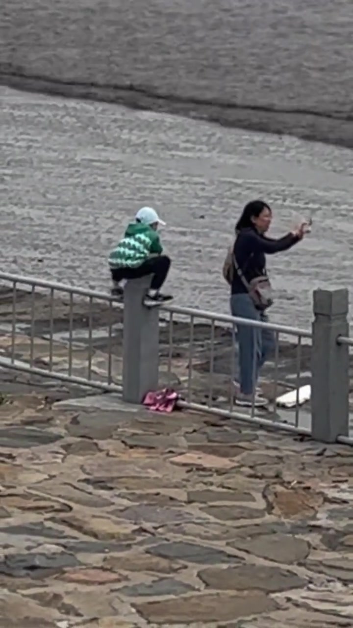 太危险！妈妈带着小孩越过围栏观潮！路人提醒依然不动