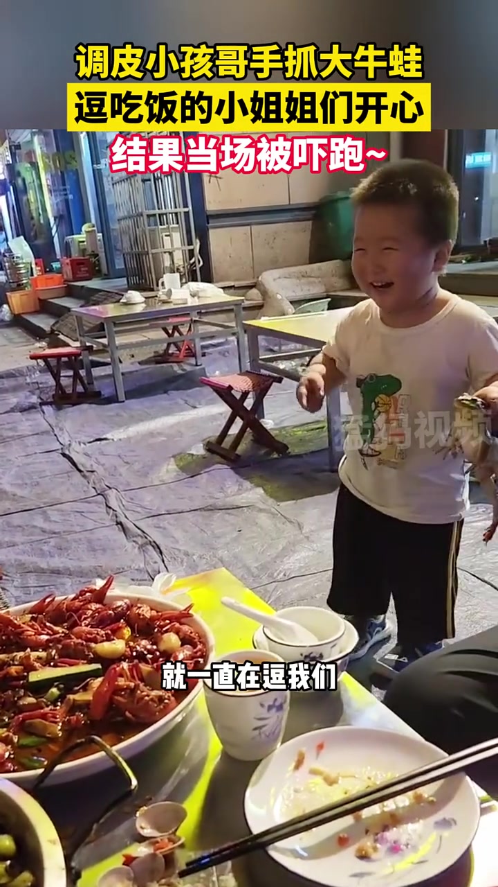 调皮小男孩手拿大牛蛙逗吃饭的小姐姐开心