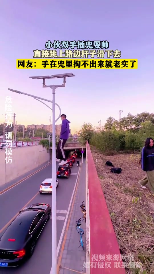 小伙双手插兜耍帅，直接跳上路边杆子滑下去