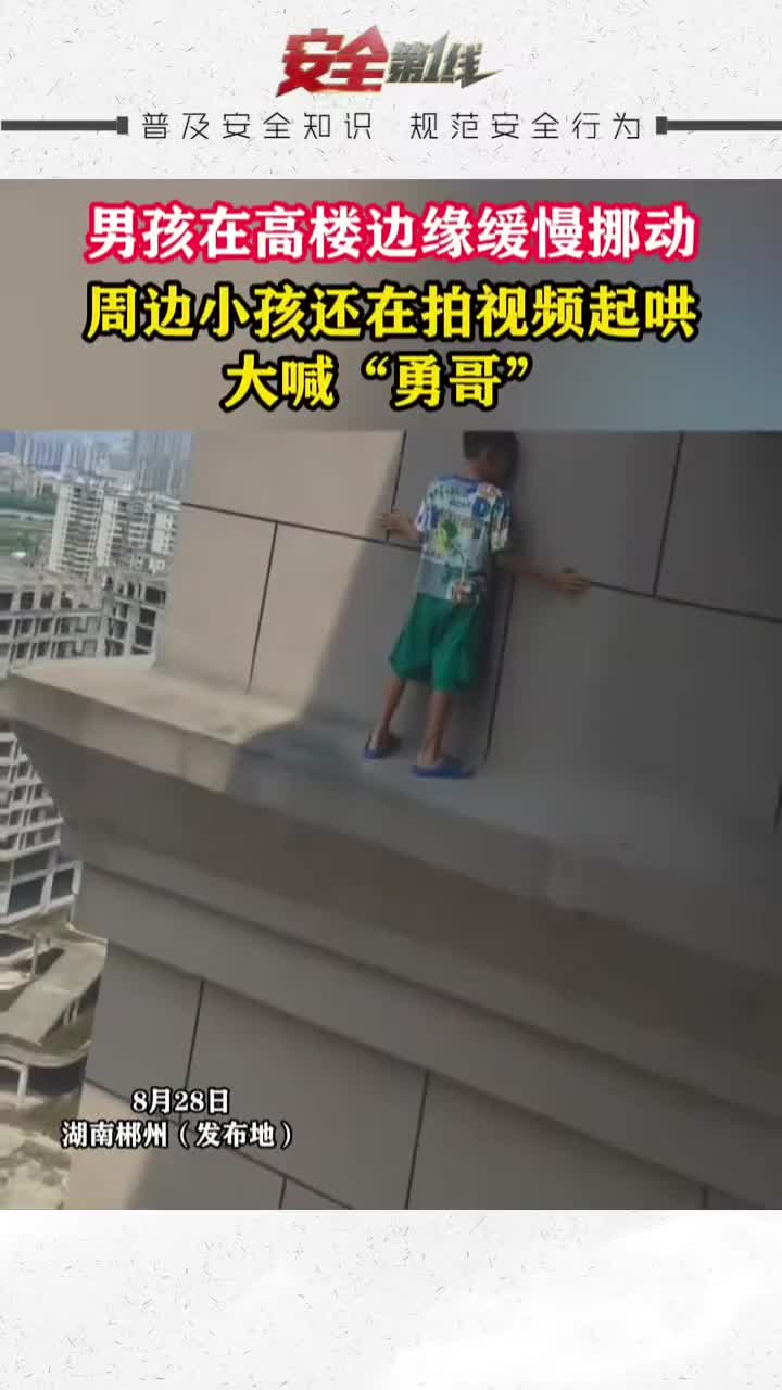 男孩在高楼边缘缓慢挪动，周边小孩还在拍视频起哄大喊“勇哥”
