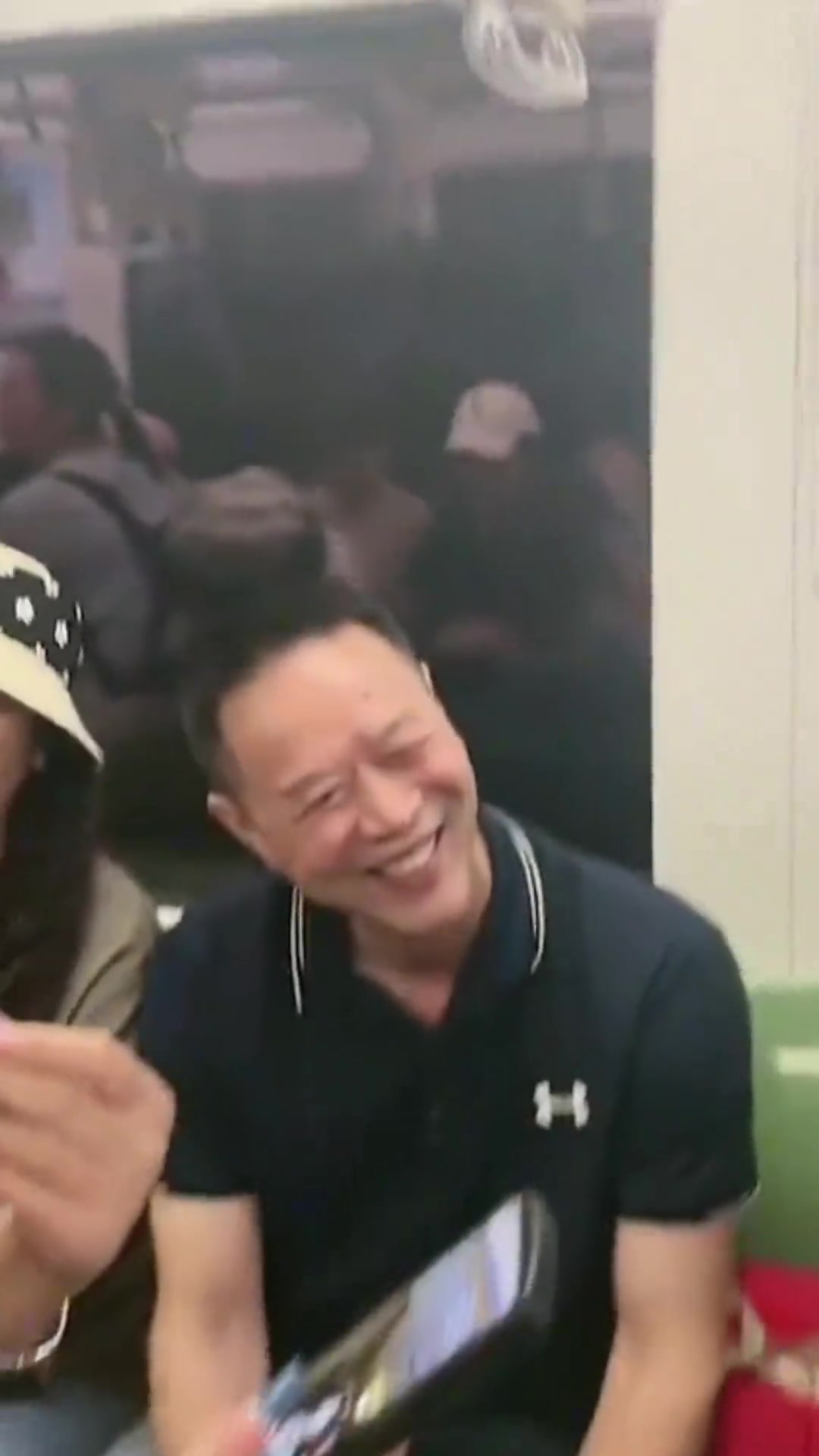 男子将行李放在座位上，旁边人都站着，他还洋洋自得的跟别人聊天