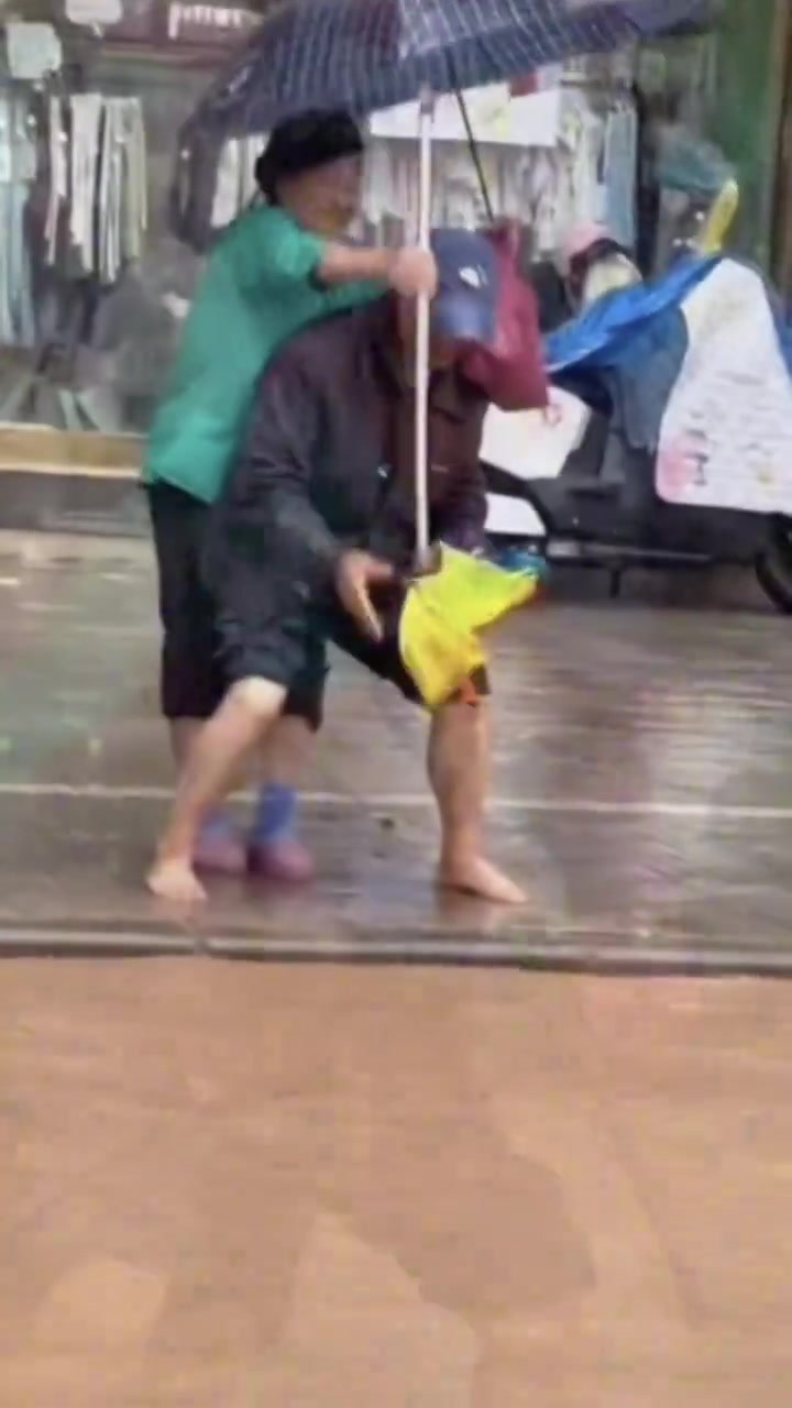 下暴雨道路被淹，老人脱鞋背着老伴过马路！
