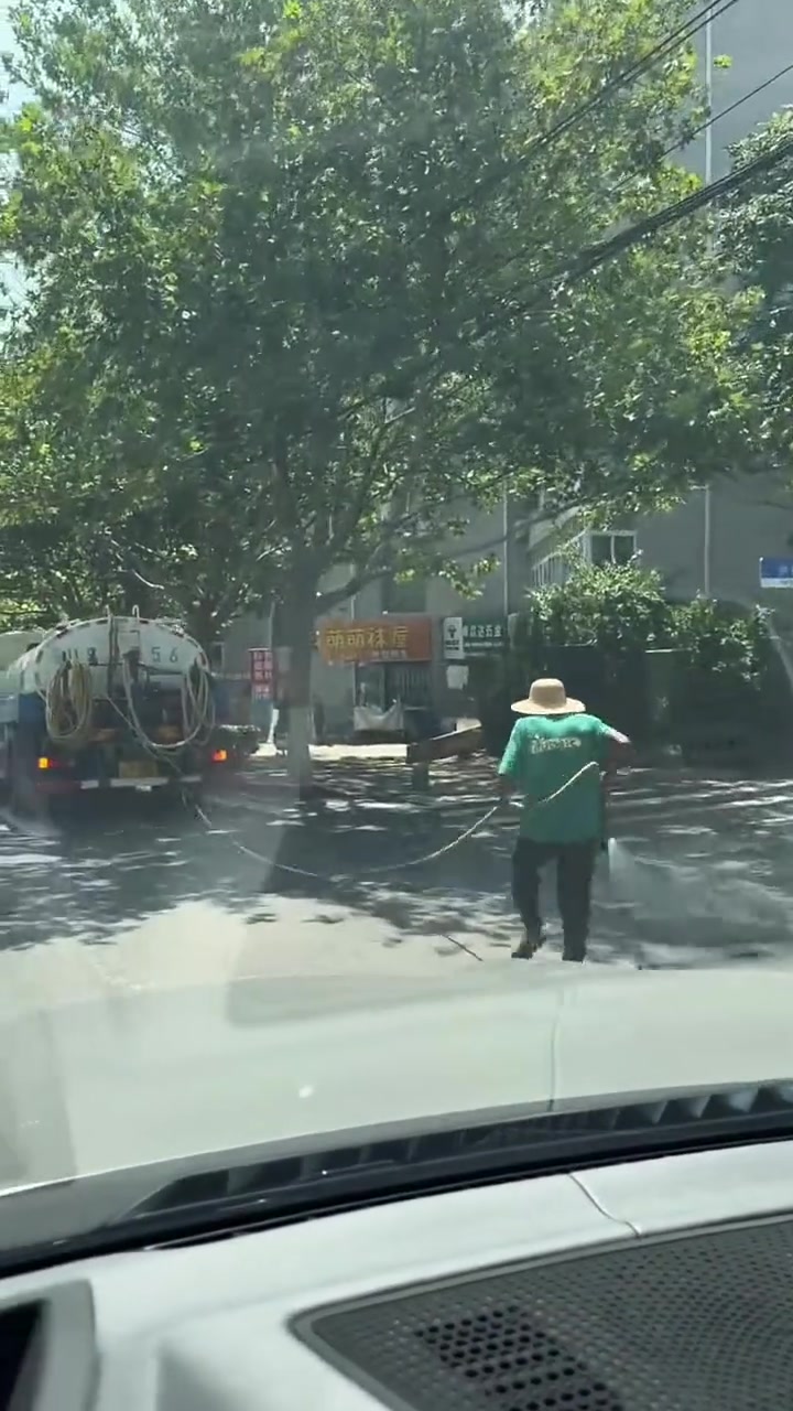 一名老人拿着水管跟在洒水车后面跑！网友心疼大爷！
