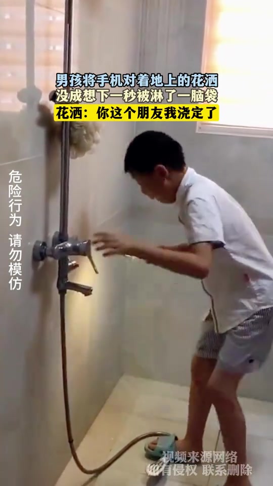 男孩将手机对着地上的花洒，没成想下一秒被淋了一脑袋