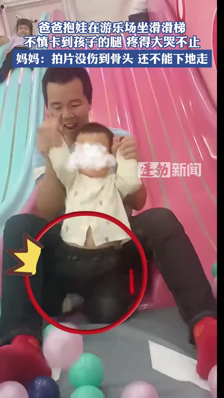 爸爸抱娃在游乐场坐滑滑梯，不慎卡到孩子的腿疼得大哭不止！
