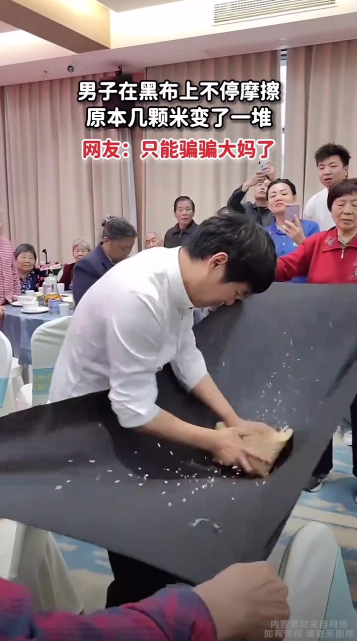 男子在黑布上变魔术，让周围的大妈好奇凑上去