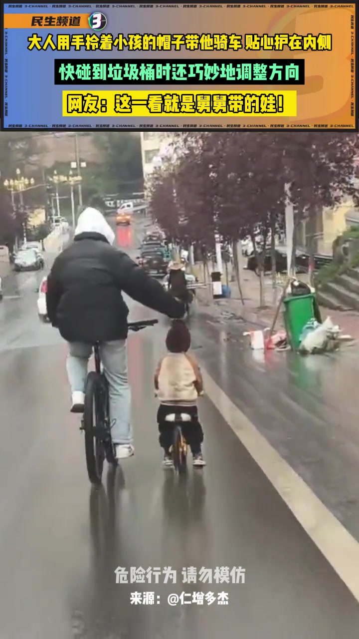 大人用手拎着小孩的帽子带他骑车，贴心护在内侧！
