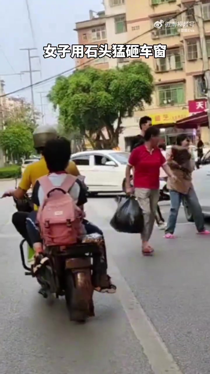 女子用石头猛砸车窗，黑衣男子误以为她要救人，上前帮忙