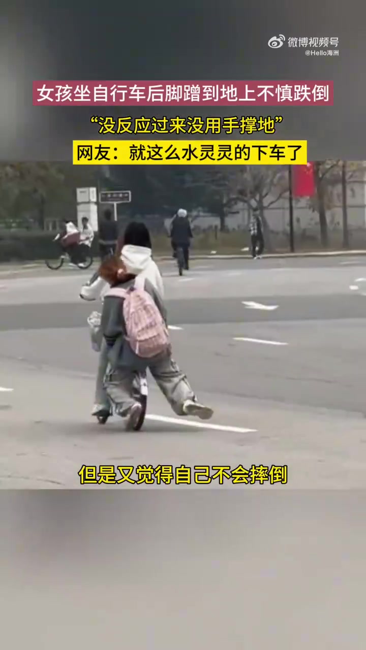 女孩坐在自行车后座，结果脚不小心蹭到地摔倒了