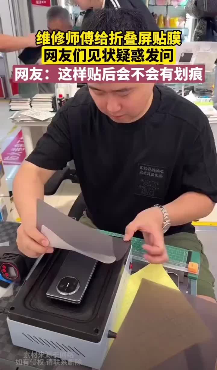师傅手法娴熟的给折叠屏手机贴背膜