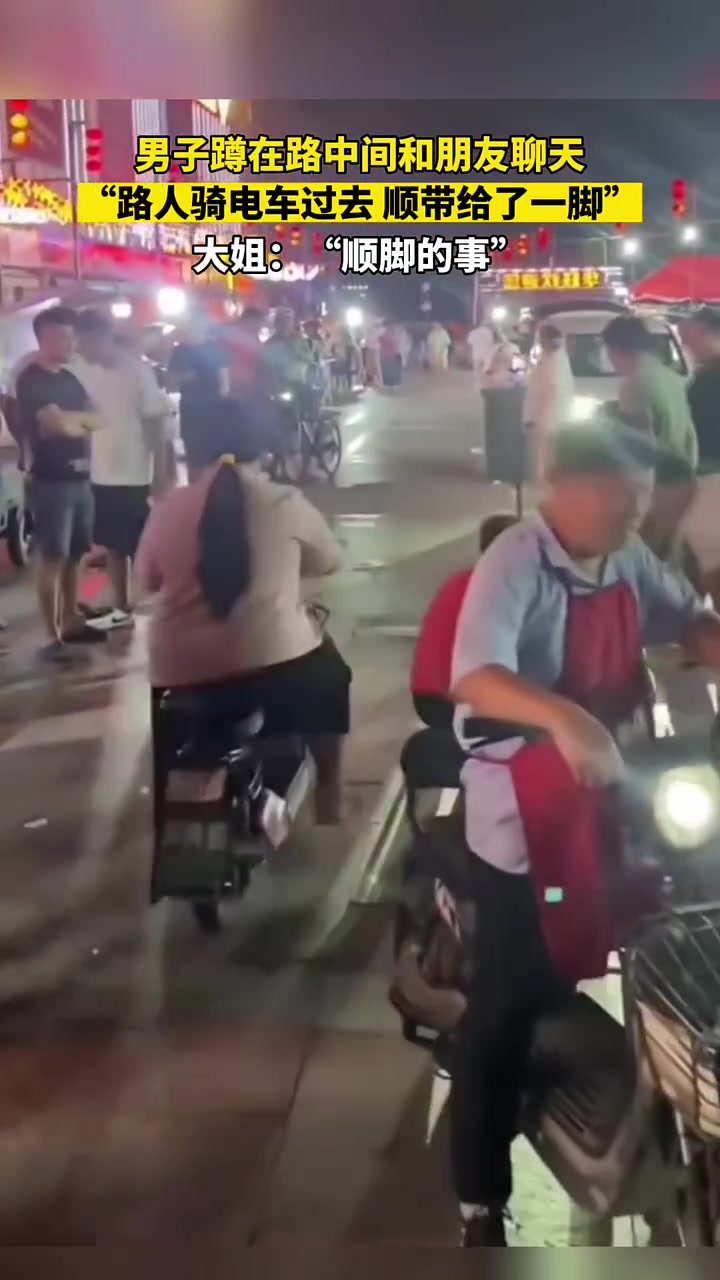 男子蹲在路中间和朋友聊天，路人骑车过去顺带给了一脚