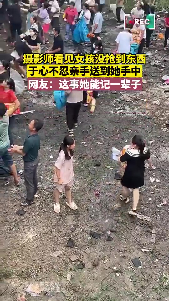 摄影师看见女孩没抢到东西，于心不忍亲手送到她手中