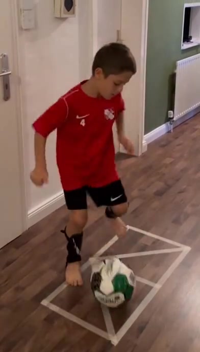 练习双脚拉球的小男孩，我们有几个小朋友能做到这样