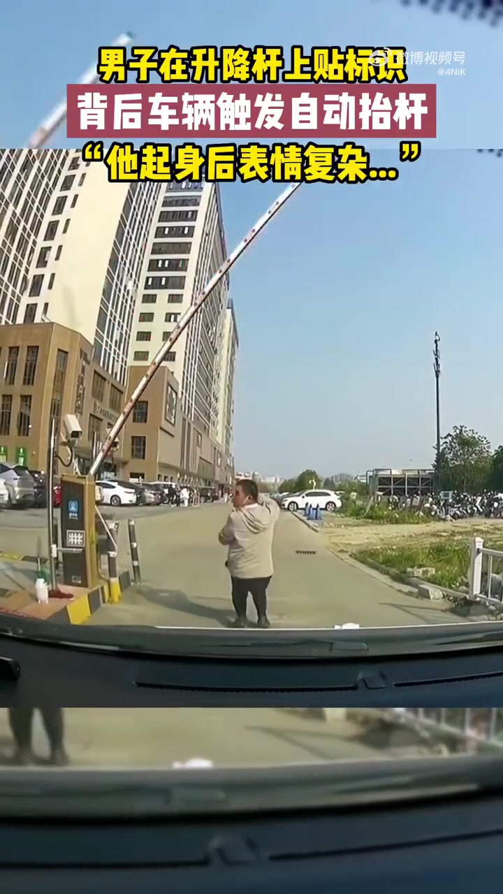 男子在升降杆上贴标识，背后车辆触发自动抬杆