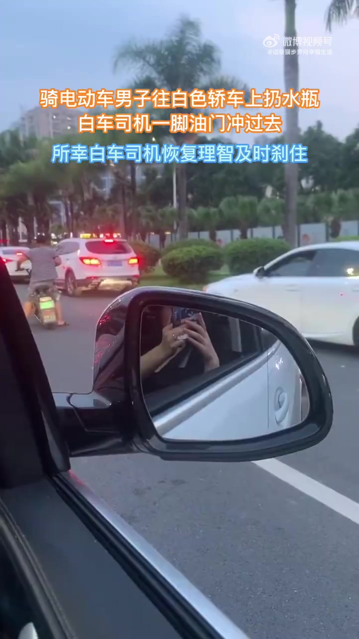 骑电动车男子往白色轿车上扔水瓶，白车司机一脚油门冲过去