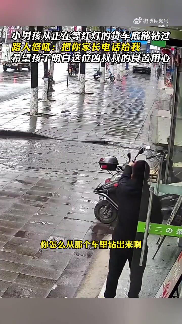 太危险！小男孩从正在等红灯的货车底部钻过