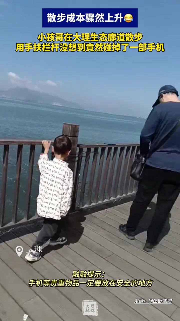 小孩哥在廊道散步，用手扶栏杆没想到竟然碰掉了一部手机