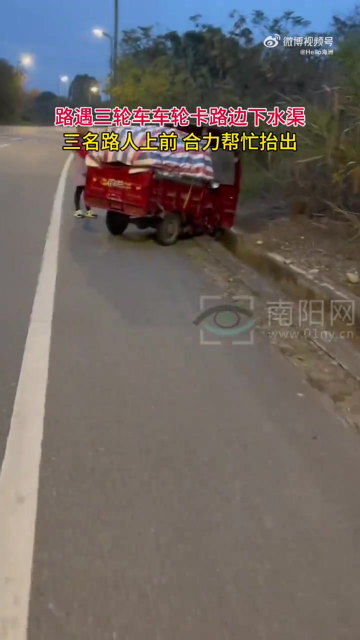 路遇三轮车车轮卡路边下水渠，三名路人上前合力帮忙抬出