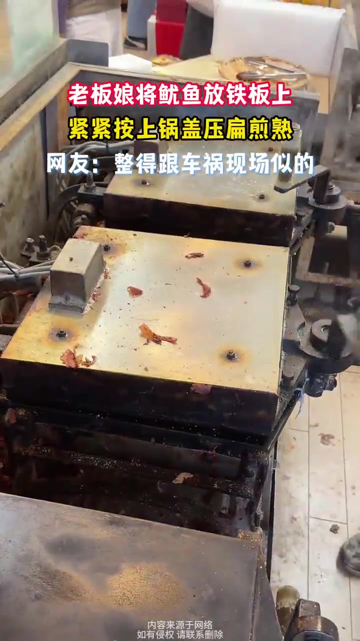 老板娘将整条鱿鱼放铁板上，紧紧按上锅盖煎熟