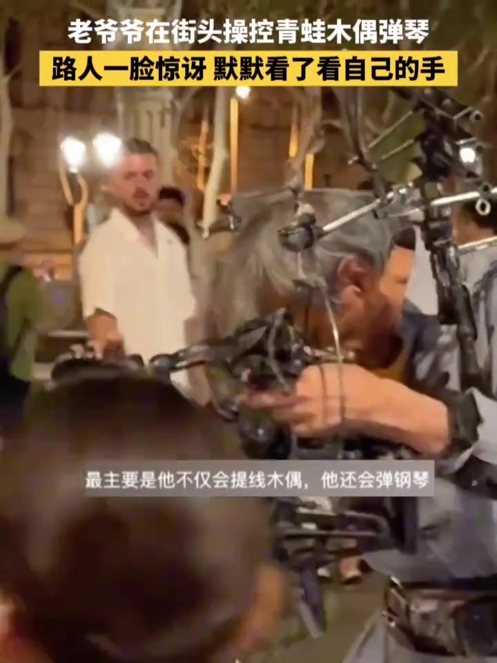 老爷爷在街头操控青蛙木偶弹琴