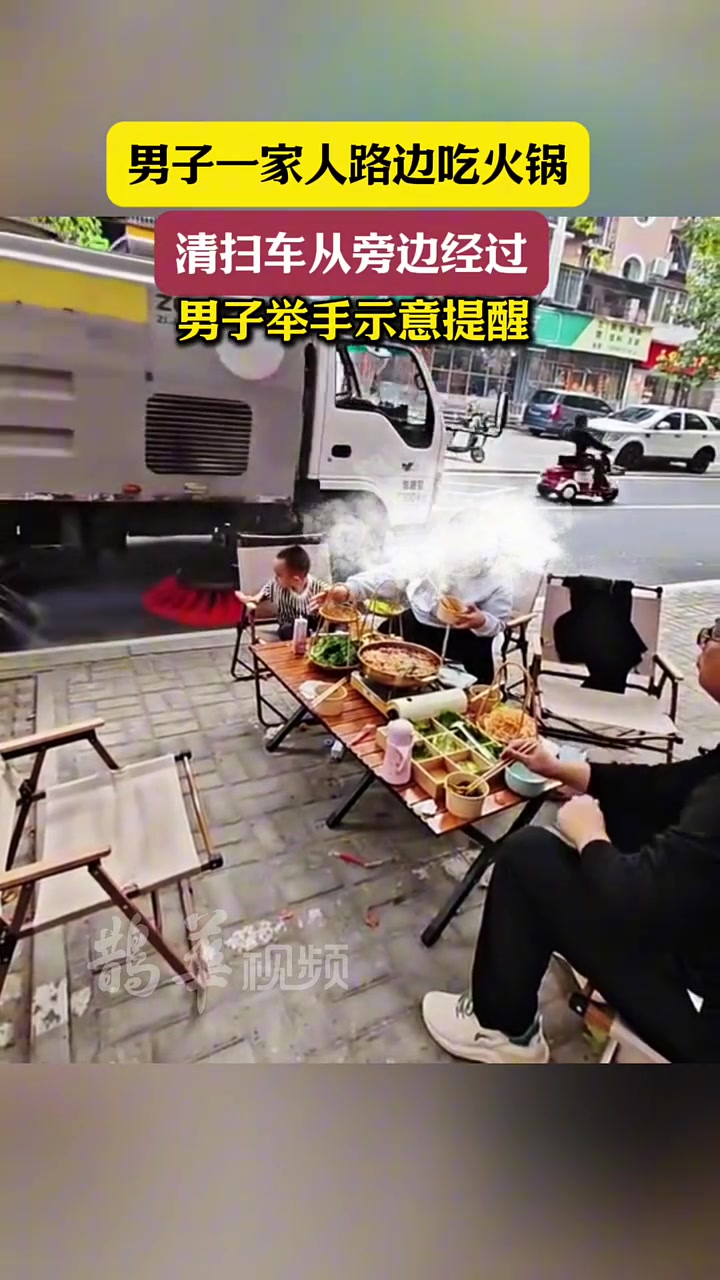 男子一家人在路边吃火锅，清扫车从旁边经过，男子举手示意提醒