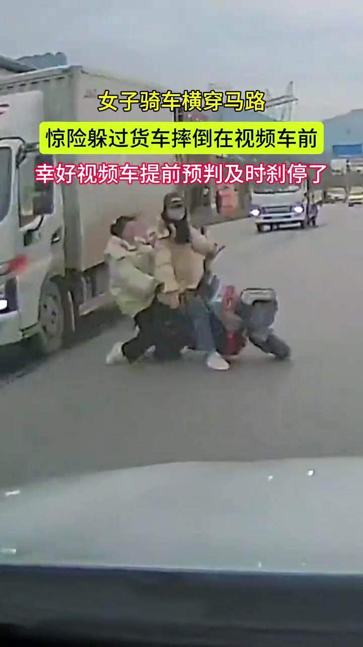 女子骑车横穿马路惊险躲过货车摔倒在视频车前