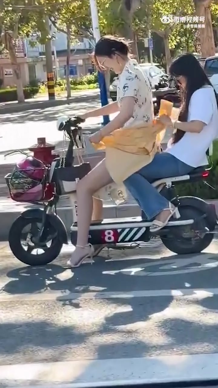 女生穿旗袍骑电动车担心走光用衣服遮挡