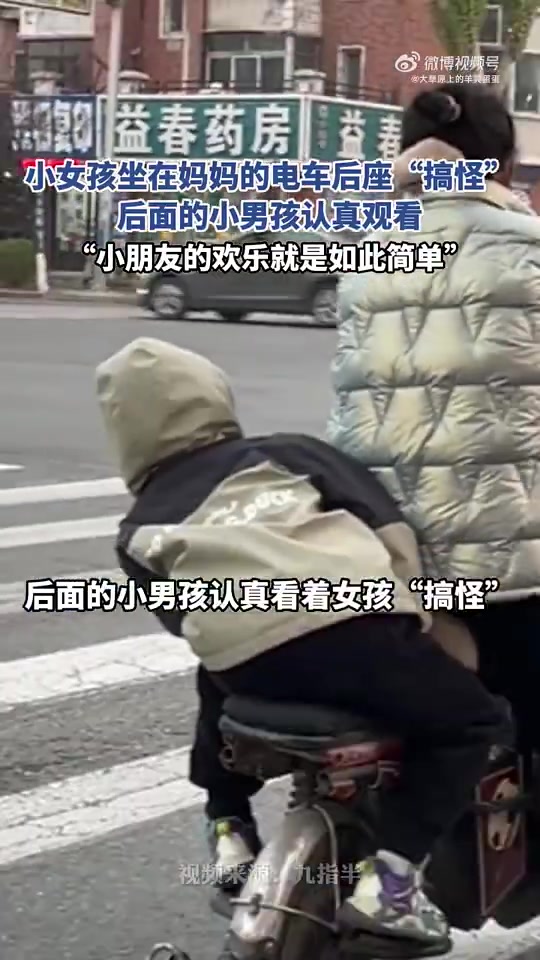 小女孩坐在妈妈的电车后座“搞怪”，后面的小男孩认真观看