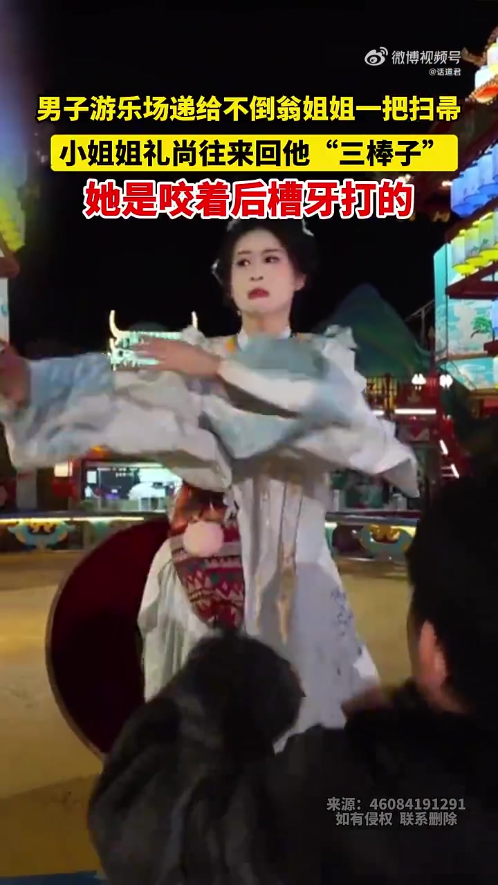 男子游乐场递给不倒翁姐姐一把扫帚，小姐姐礼尚往来回他三棒子