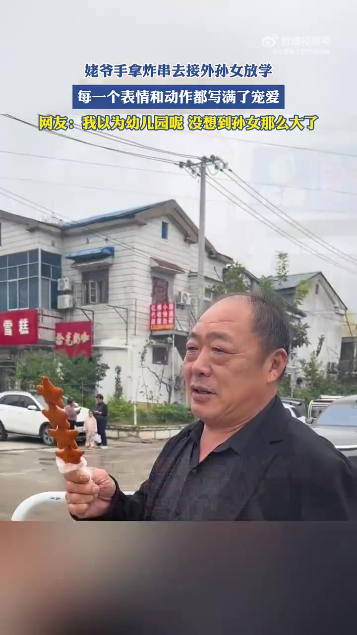 姥爷手拿炸串去接外孙女放学，每一个表情和动作都写满了宠爱