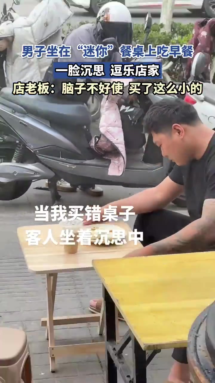 男子坐在“迷你”餐桌上吃早餐，一脸沉思，逗乐店家！