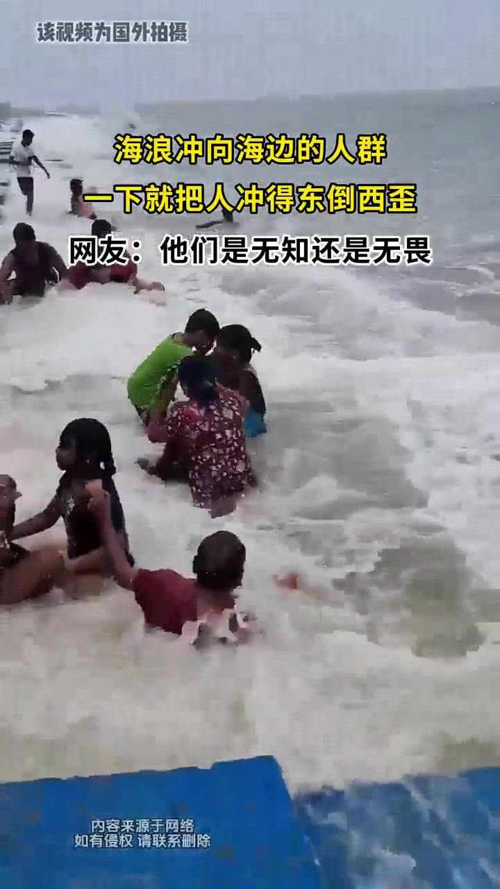 海浪冲向海边的人群一下就把人冲得东倒西歪