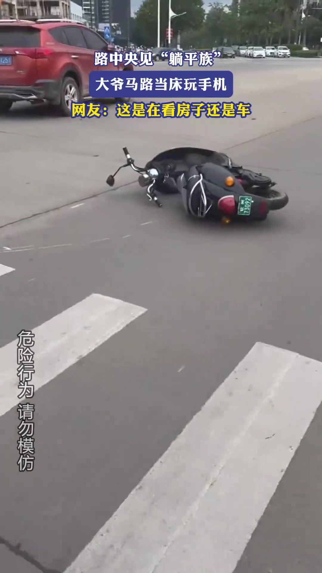 路中央见躺平族，大爷马路当床玩手机，网友：这是在看房子还是车