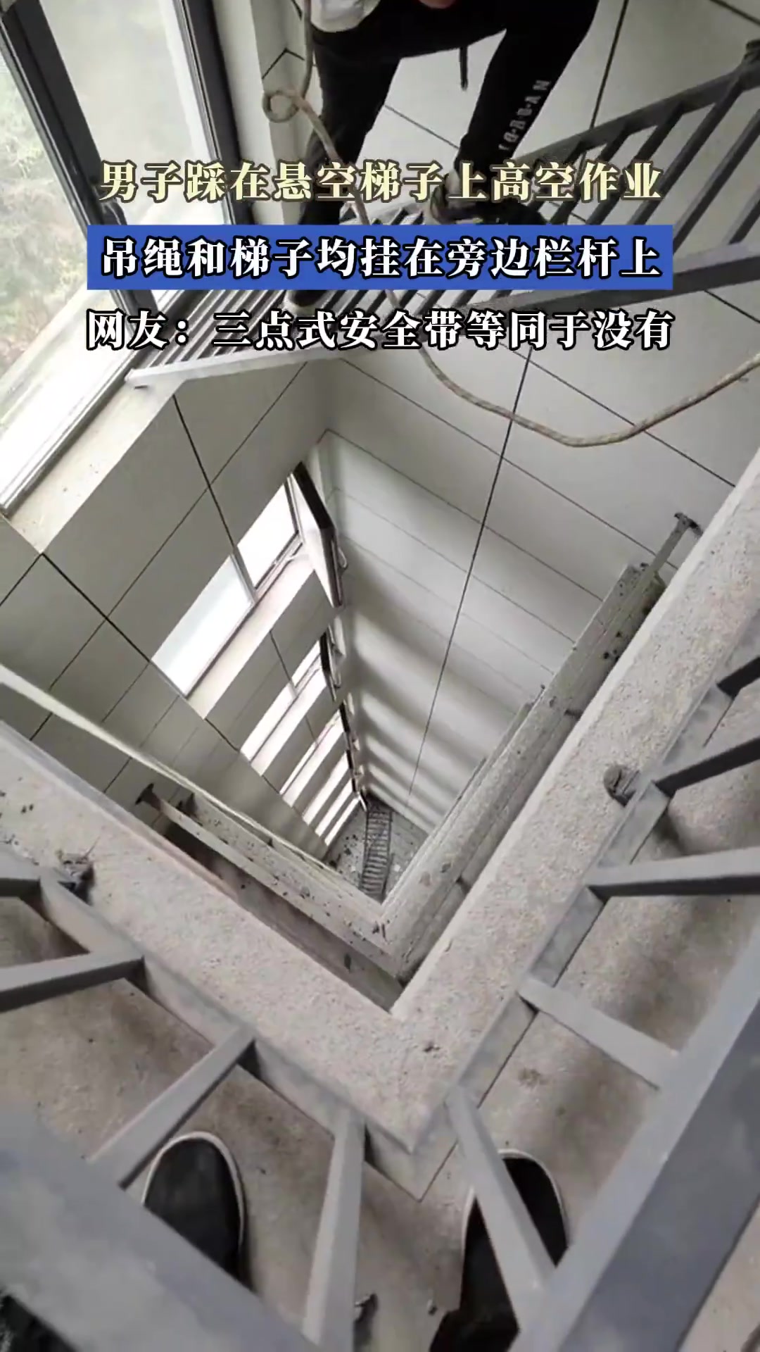 男子踩在悬空梯子上高空作业，吊绳和梯子均挂在旁边栏杆上！