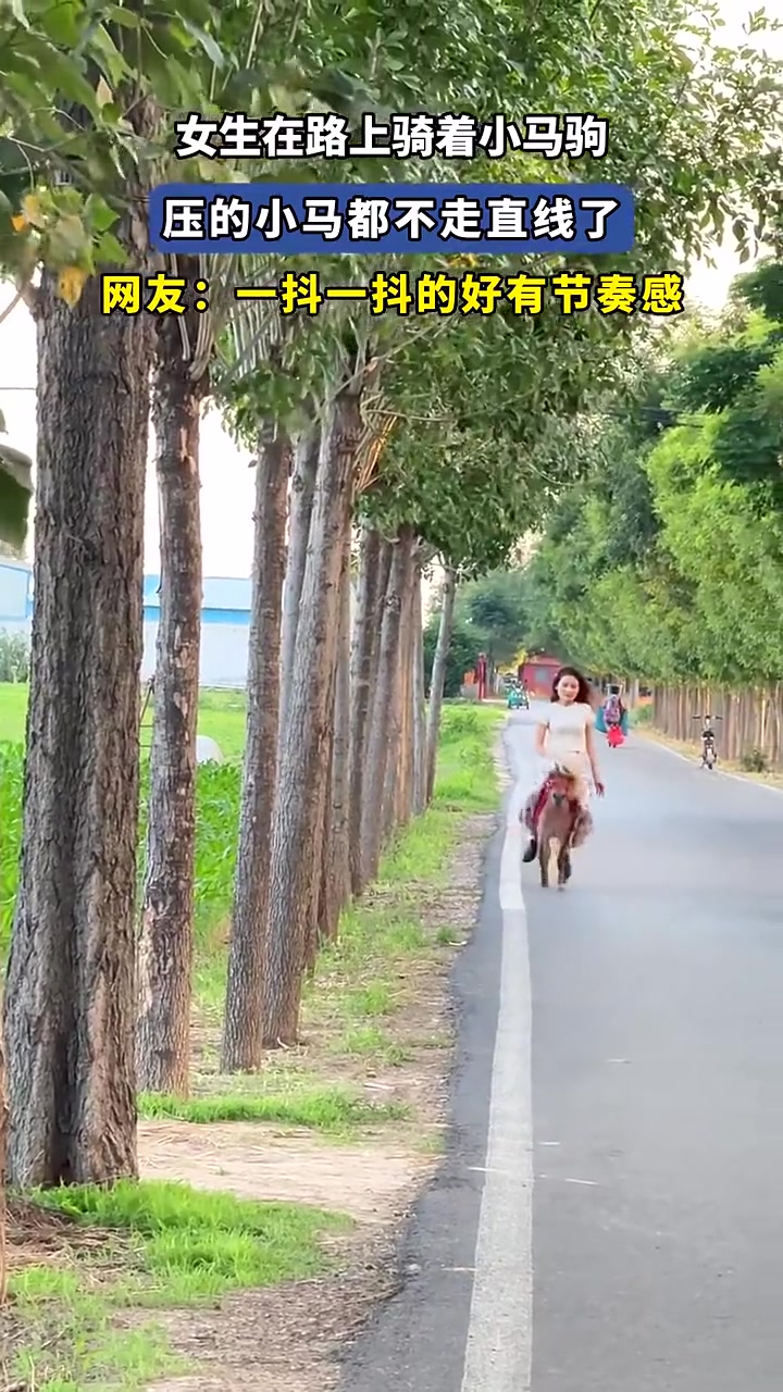 女生在路上骑着小马驹,压得小马都不走直线了