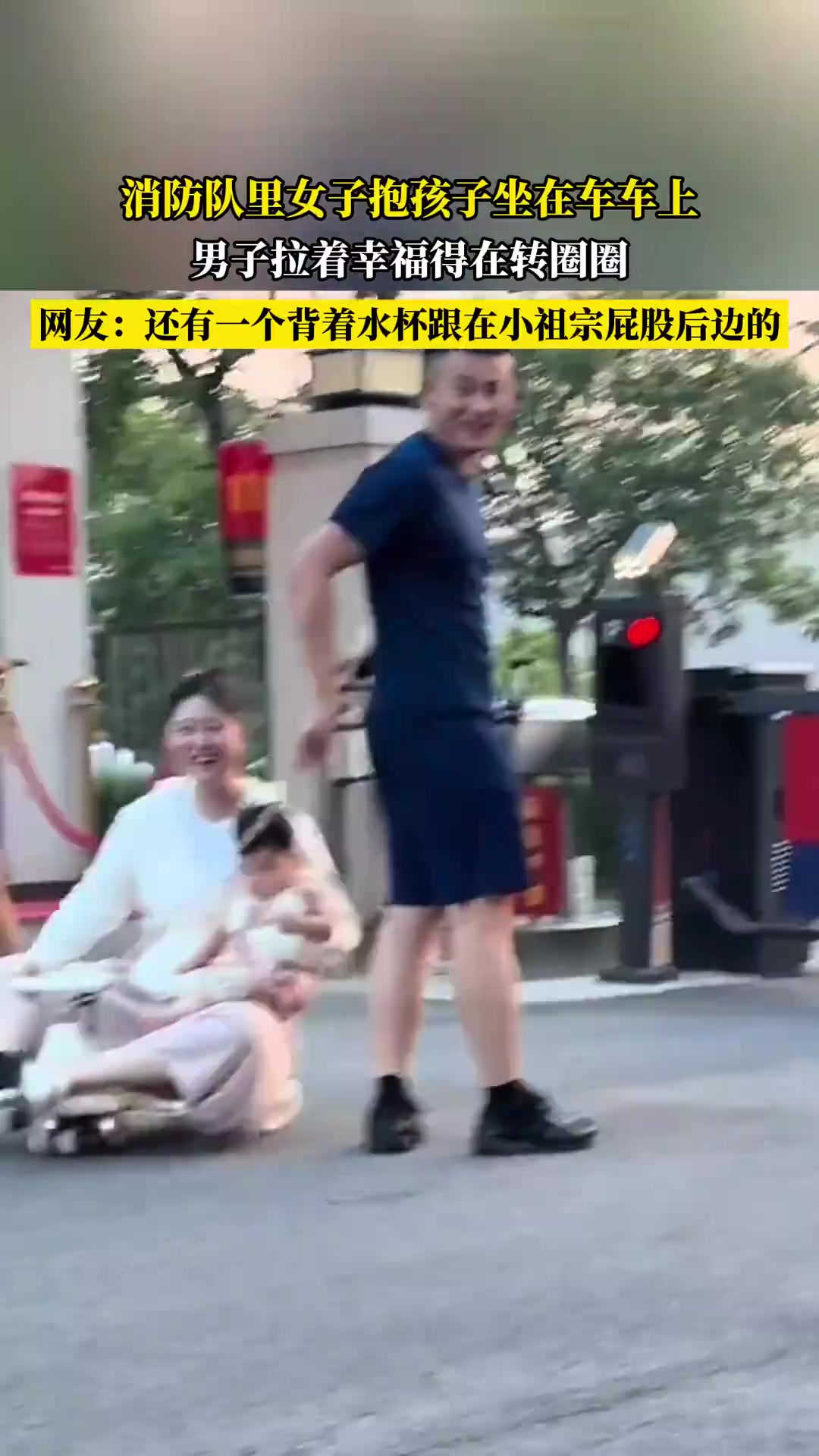 消防队里女子抱孩子坐在车车上，男子拉着幸福得在转圈圈！！