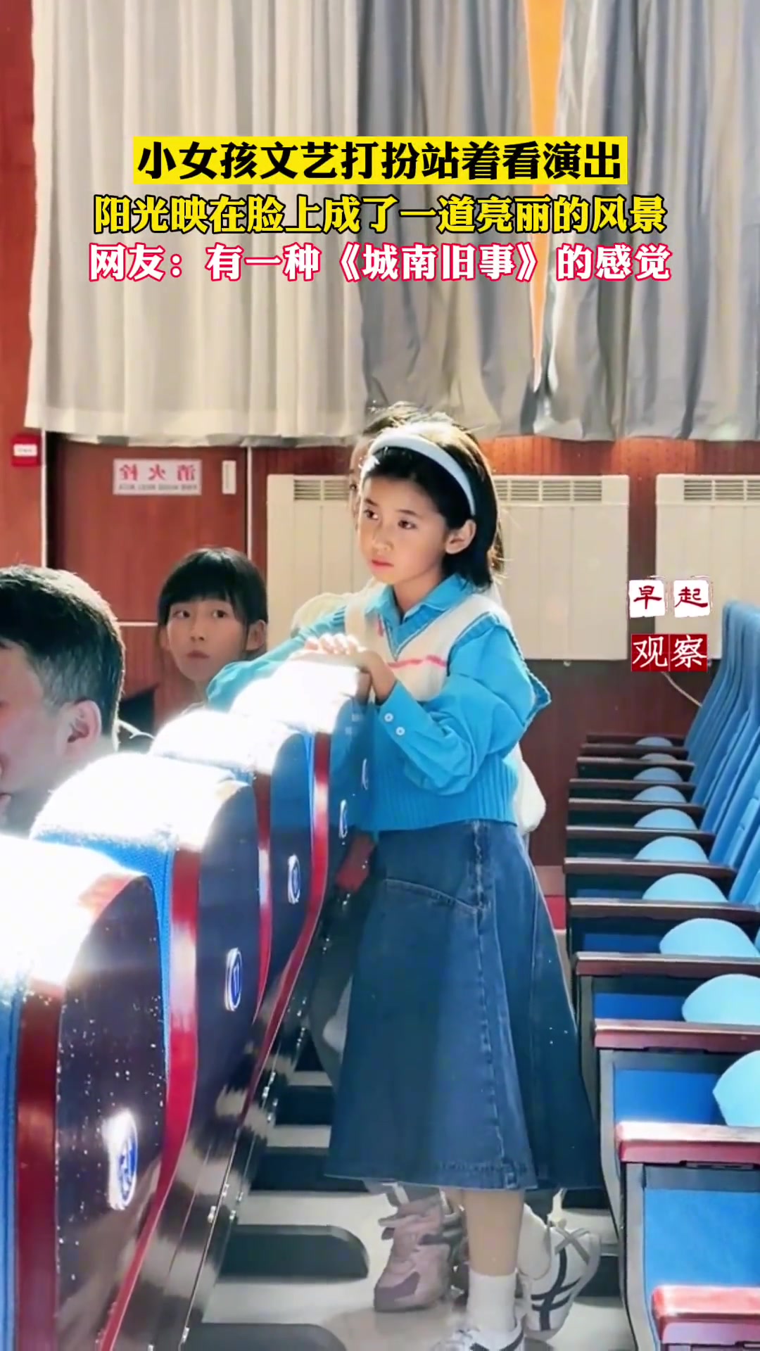 小女孩站在报告厅里看演出，有种电影感的恬静美