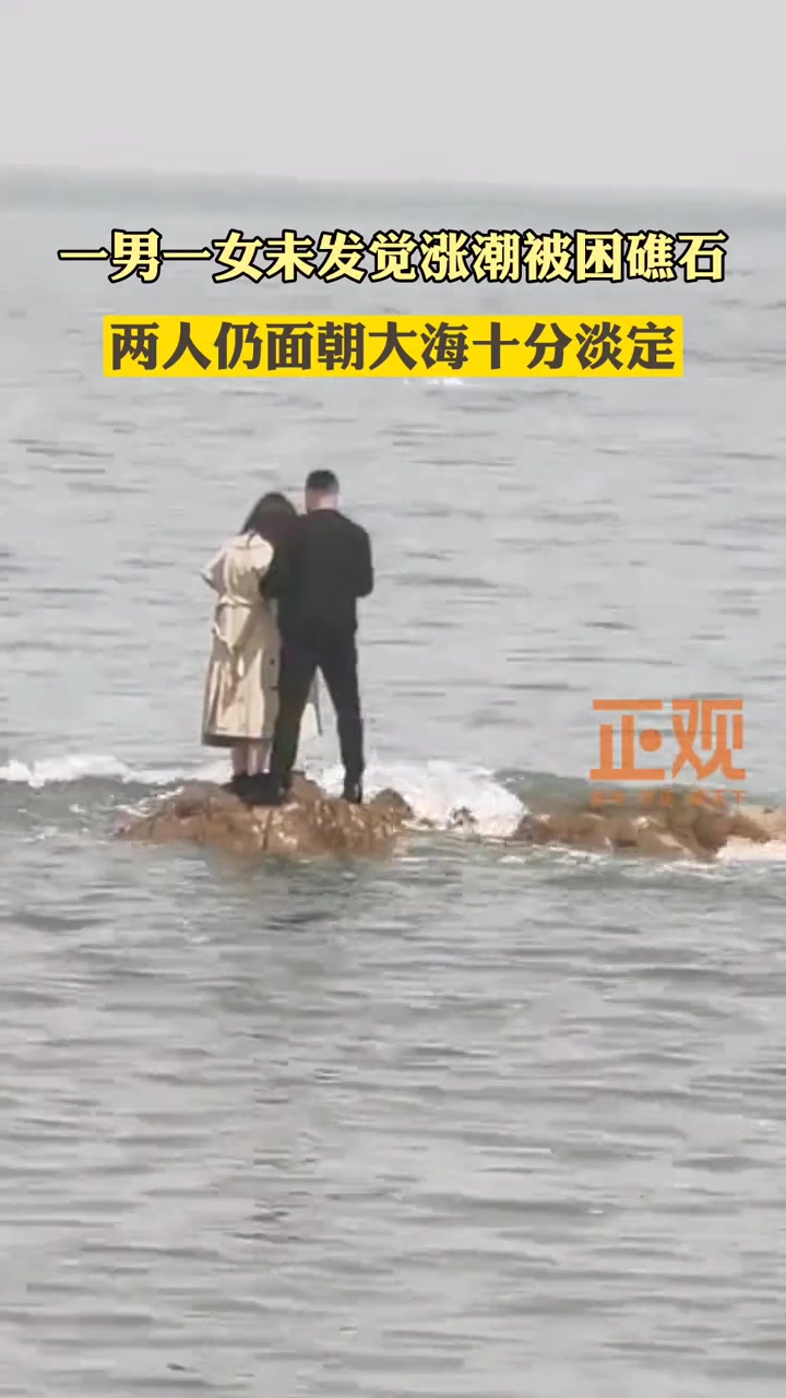 一男女未发觉涨潮被困礁石 两人仍面朝大海十分淡定