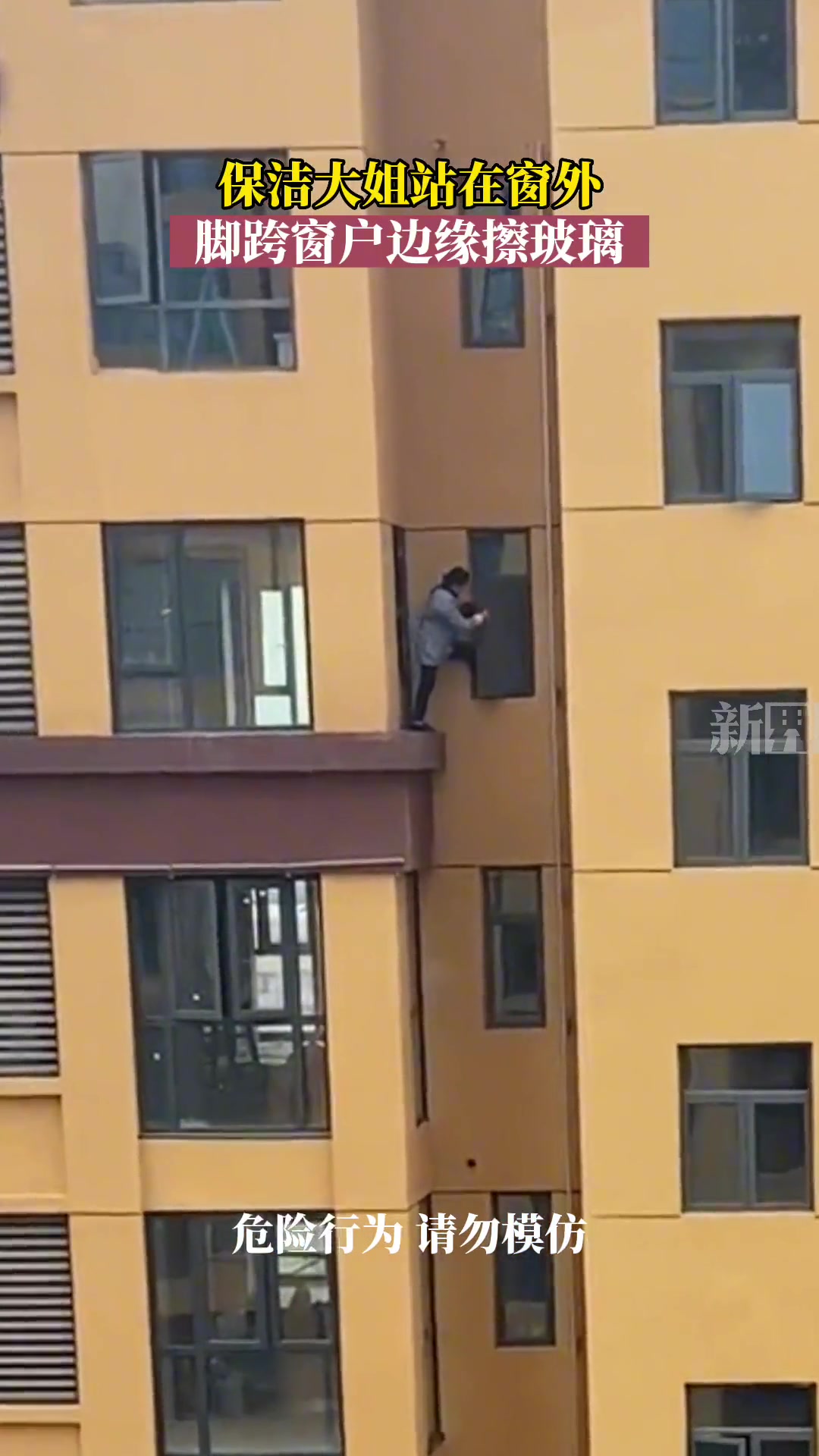 保洁大姐站在窗外，脚跨窗户边缘擦玻璃