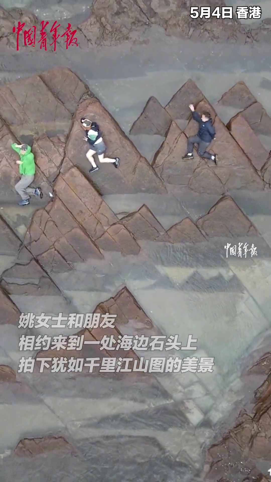 女子和朋友在海边石头上，拍下犹如千里江山图的美景