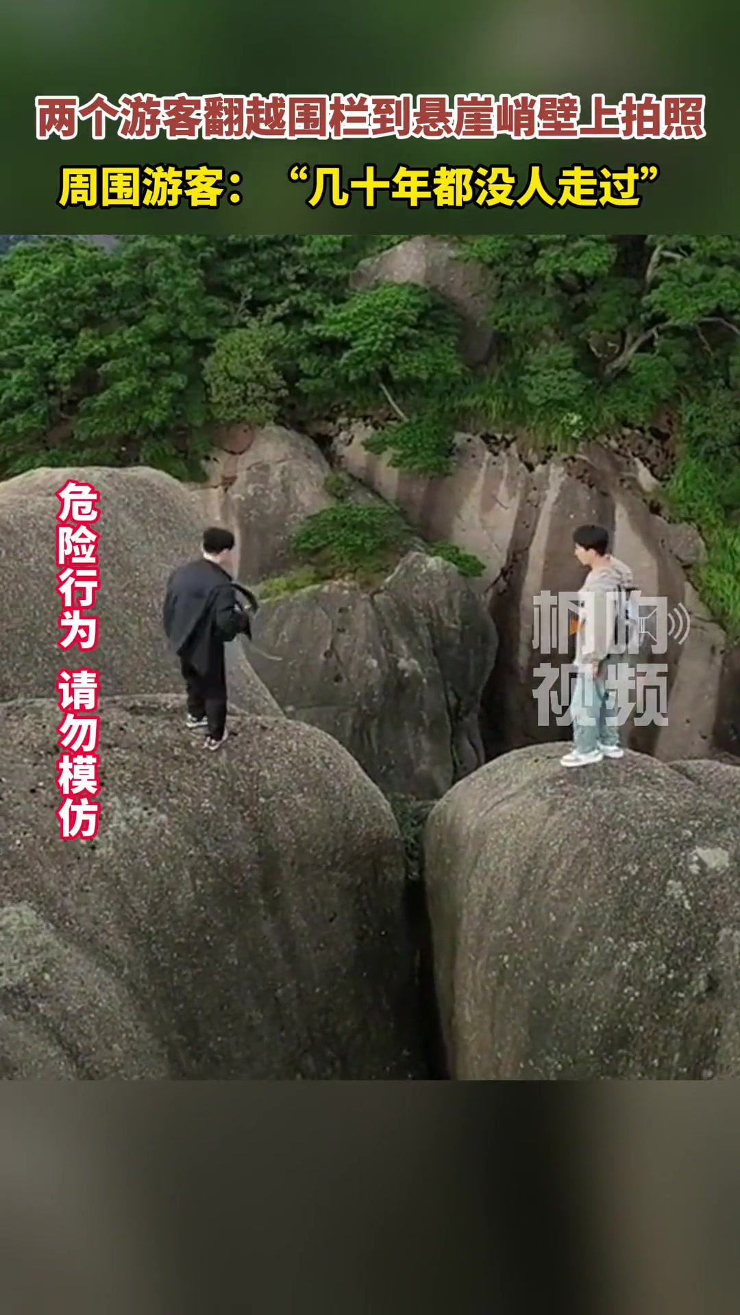 两个游客翻越围栏到悬崖峭壁上拍照