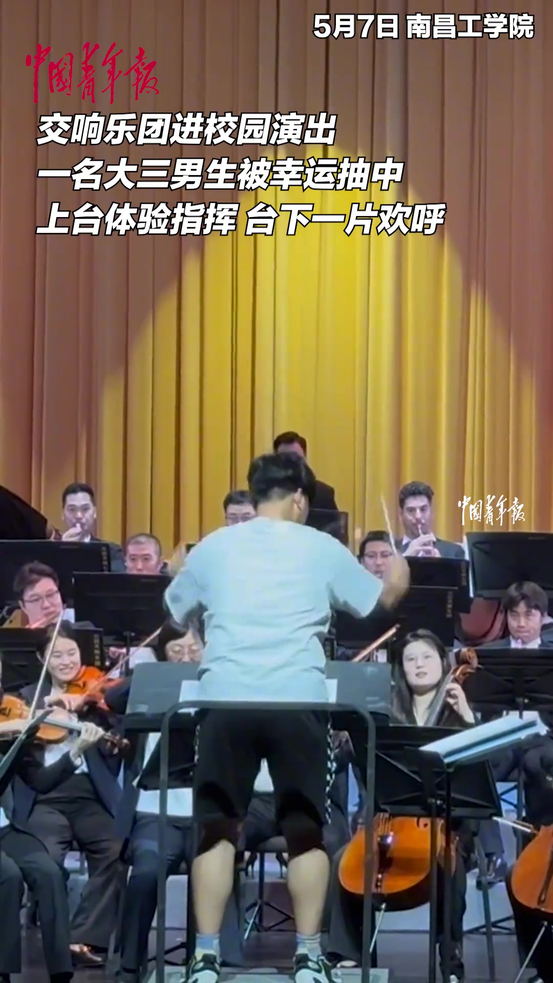 大三男生被幸运抽中上台体验指挥，台下一片欢呼。