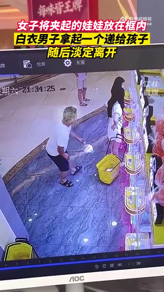 这不就是偷窃吗？男子将女子放在框里的娃娃拿起一个递给孩子