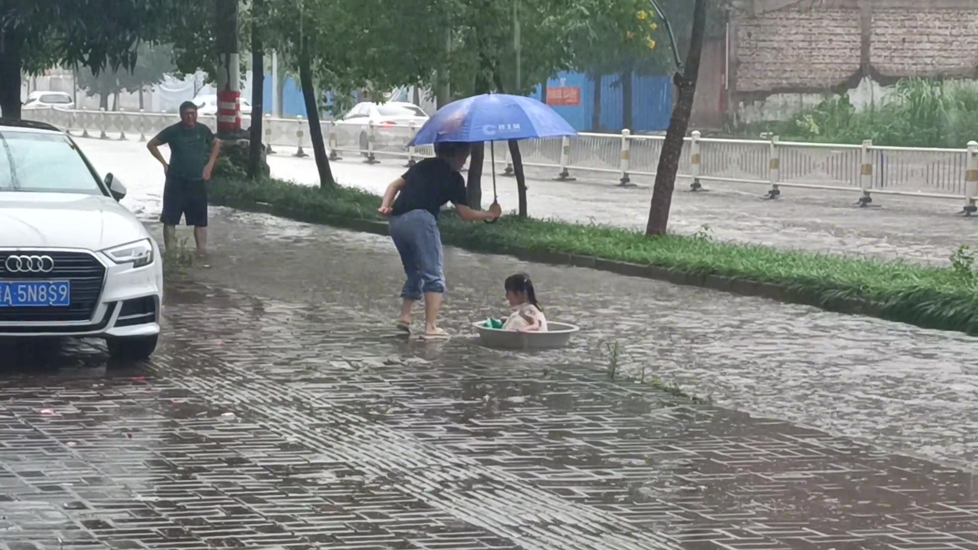 旁边有妈妈在帮她撑伞陪她玩，下面有爸爸正等着保护她