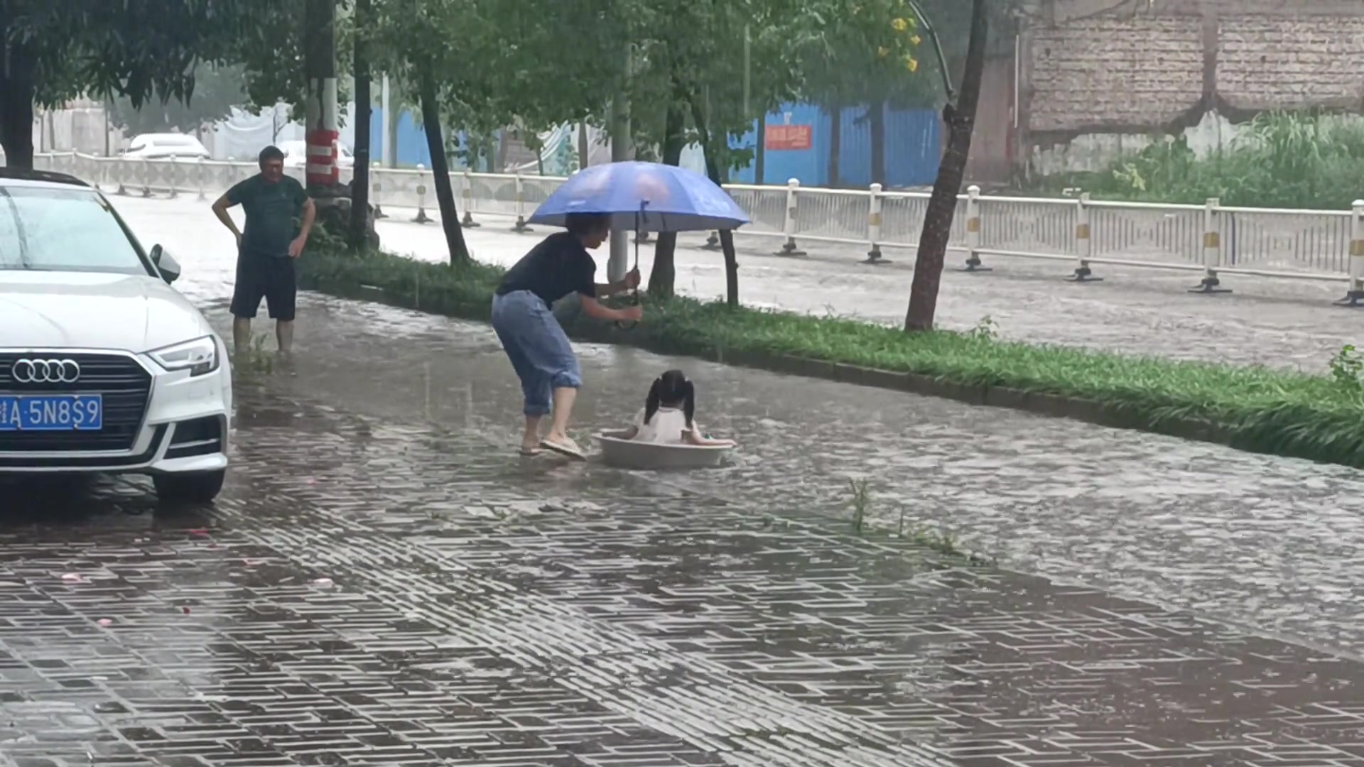 旁边有妈妈在帮她撑伞陪她玩，下面有爸爸正等着保护她